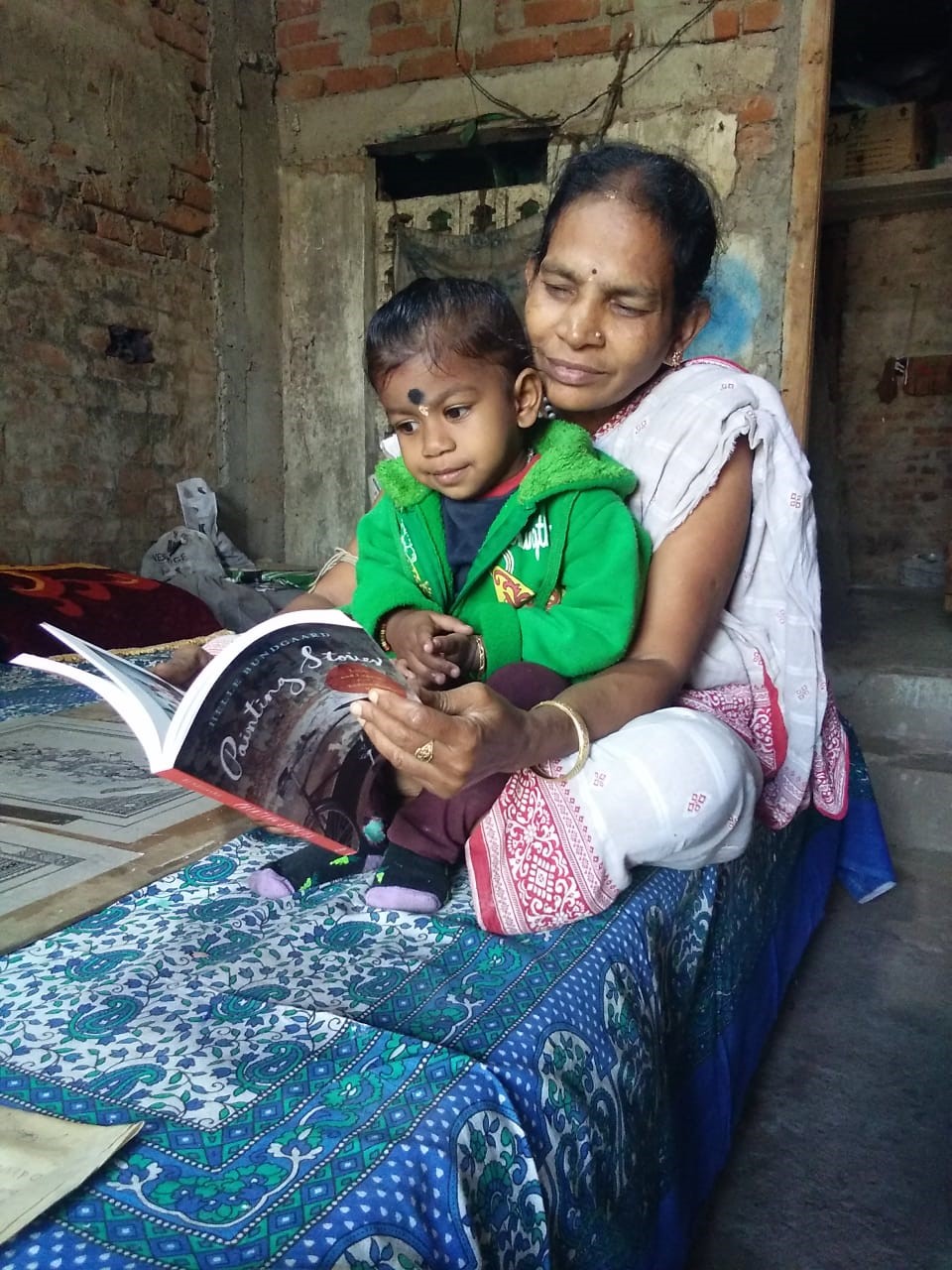 Sula with her granddaughter looking at Painting Stories